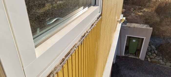 Närbild av gul aluminiumfasad från 2025 med synliga bubblor under färgen nära ett fönster.