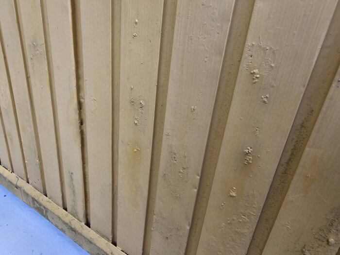 Gul aluminiumfasad med bubblor och fläckar synliga på ytan, visar tecken på korrosion under färgen.