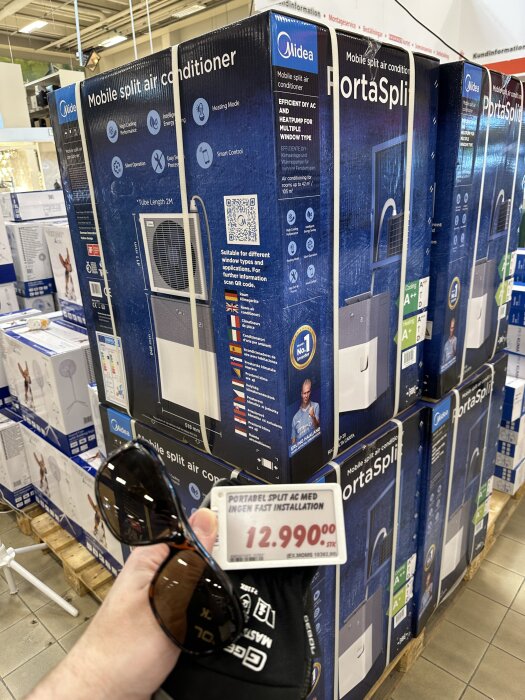 Förpackningar av Midea portabel luftkonditionering på hylla i butik, pris 12.990 kr visas i förgrunden.