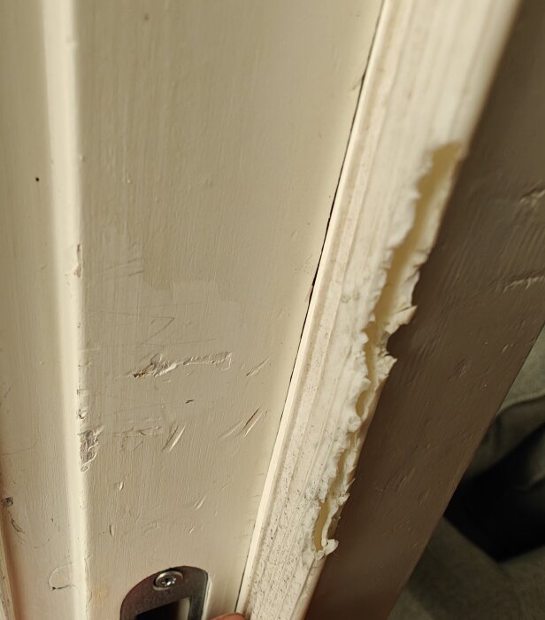Tätningslist i silikon monterad i en dörrkarm, visar slitage och skåror.