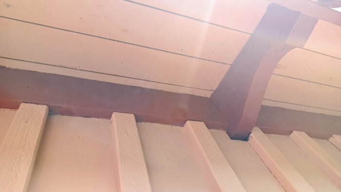 Trätak med målade paneler i ljusa och mörka kulörer, visad med betongsstrålar.