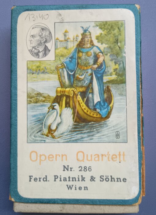 Kortlåda med operatema, en kunglig figur på en svanprydd båt i färgglad klädsel, med texten "Opern Quartett" från Ferd. Piatnik & Söhne.