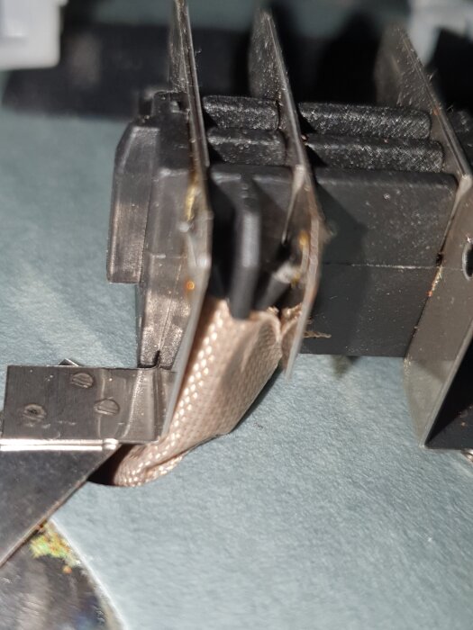 Bilden visar insidan av ett batteri med kopplingar och en tunn kabel synlig. Metallytor och batteriets konstruktion är i fokus.