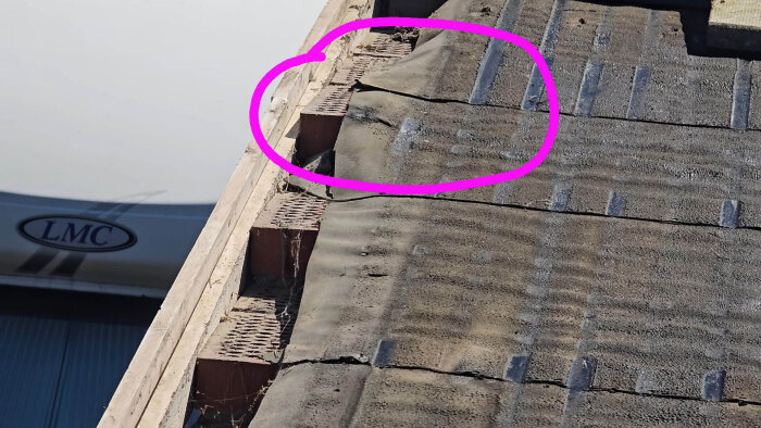Tegeltak med delvis borttagen duk, tegelstenar och takduk synliga, rosa markering visar ett problemområde vid takfoten.