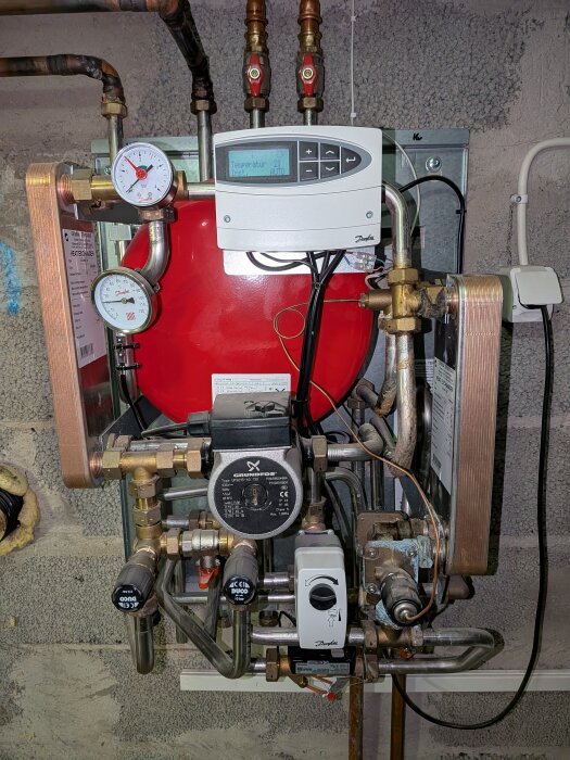 Ett komplicerat system av rör, ventiler och tryckmätare i en byggnad, med en kontrollpanel och en värmepump.