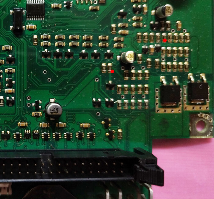 Närbild av ett kretskort med olika komponenter, inklusive kondensatorer, resistorer och kontakter, med fokus på potentiellt brända resistorer.