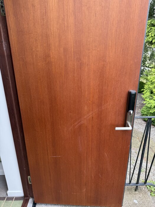 Ytterdörr med solblekt och matt träyta, handtag till höger.