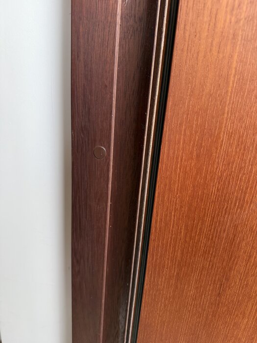 Närbild av dörrkarm i mörkt trä med en yttersida som är matt och solblekt.