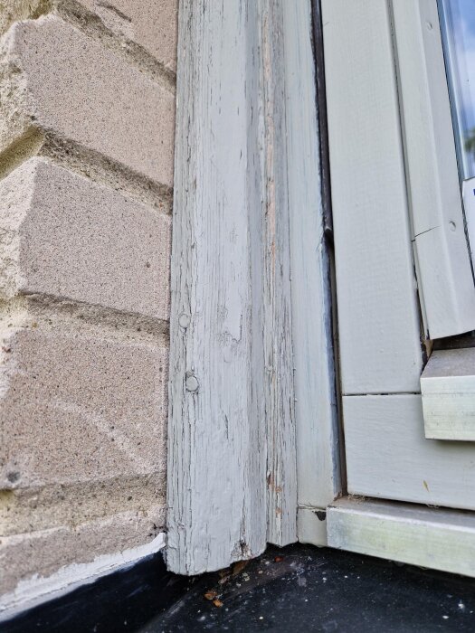 Födret vid ett fönster med flagnande färg och sprickor, intill en tegelvägg. Diskuteras om träet ska bytas ut eller underhållas.