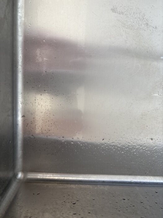 Närbild på en blank diskho i metall med fläckar och avlagringar som inte går bort med bikarbonat.