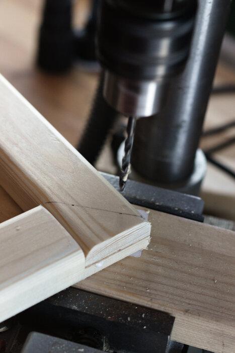 En borrmaskin används för att borra hål i träkonsoler som en del av ett pågående projekt för att bygga en anpassad skohylla.