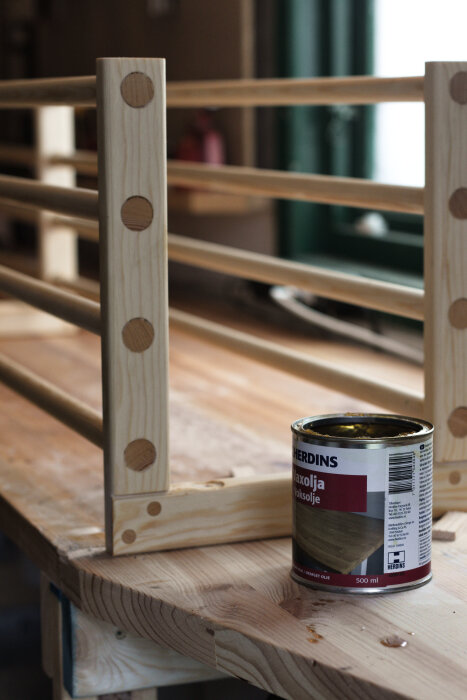 Finsnickeri: Hemmagjord skohylla av trä under konstruktion med delvis oljad yta, ses på en arbetsbänk bredvid en burk med linolja.