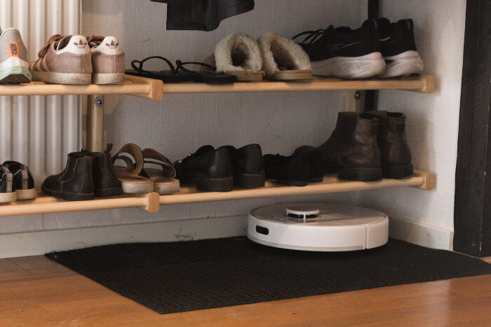Skohylla i trä med skor på två nivåer, byggd utan ben så robotdammsugare kan passera under.