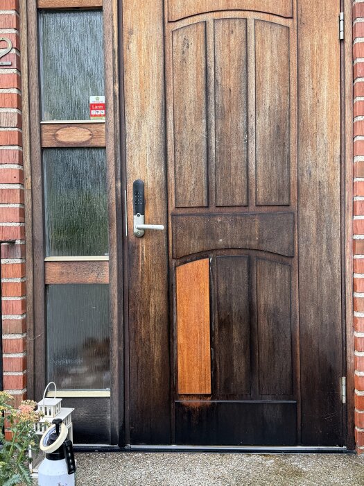 Trädörr med delvis rengjord träpanel, slipnylon och rengöringsmedel synliga på marken intill.