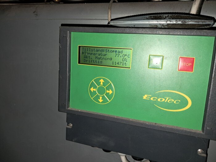 Display på EcoTec pelletsbrännare visar temperatur 77 grader och drifttid 11471 timmar, med gröna och röda knappar för start och stopp.