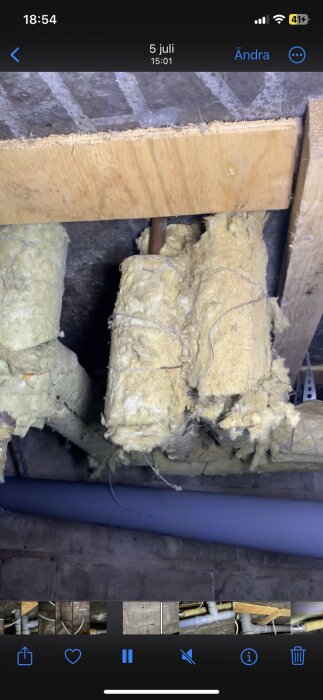 Isolerade rör med gulaktig isolering i en krypgrund med fuktproblem och närvaro av mögel samt misstänkt gammal isolering.