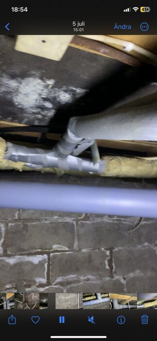 Rör i krypgrund med vitmögel på asfaltboard ovanför, grått rör och isolermaterial synligt.