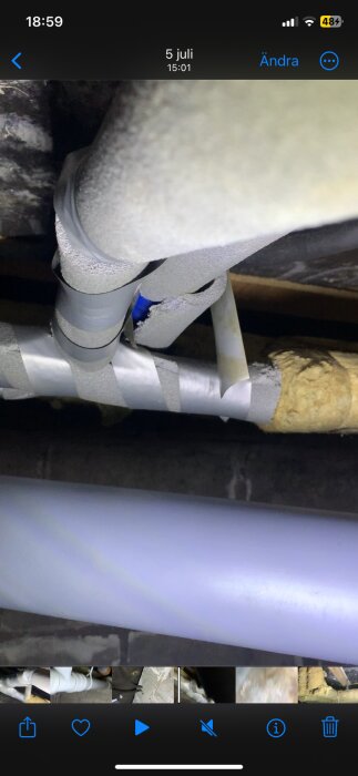 Rör med isolering i en krypgrund, tejpade fogar och synlig mögelväxt. Problem med fukt indikerat av inlägget.