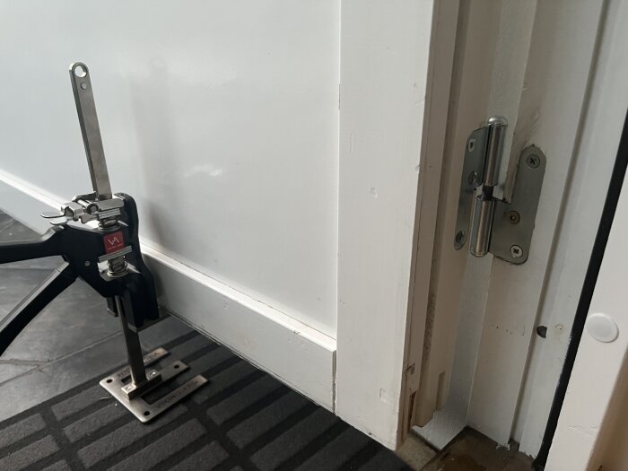 Dörrlyftverktyg håller upp dörr vid gångjärnet för att applicera smörjmedel.