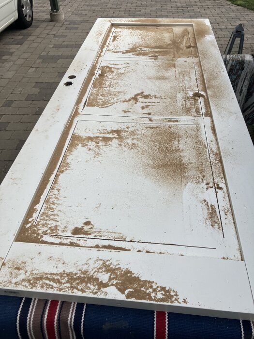 Vy över en pärlspontskiva som slipats, liggande på ett underlag med marksten i bakgrunden. Träspån spridda över ytan.