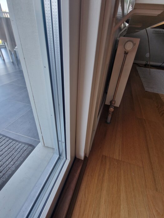 Glipa mellan altandörr och karm, med synlig ljusinsläpp och närliggande element, ovanför handtaget och på motsatt sida av gångjärnen.