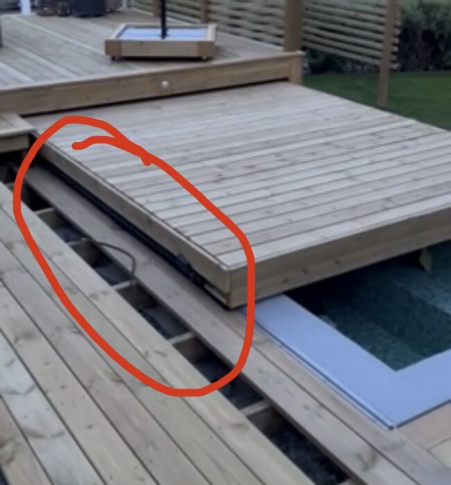 Trädäck med glapp mot pooltaket, markerat med röd cirkel; visar byggprojekt med fokus på däckets och pooltakets övergång.