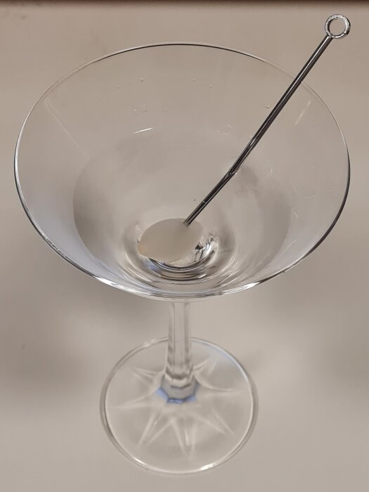 Cocktailglas med en drinkpinne i, troligen en Gibson-cocktail.