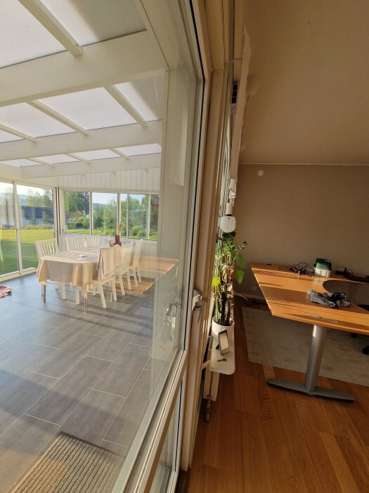 Gångjärn på en glasdörr mellan ett rum och en inglasad veranda med matbord och stolar, sett inifrån ett hem.