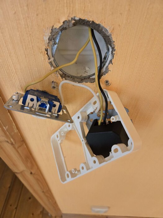 Vägguttag med dimmer och brytare, demonterade och hängande från väggen inför ommålning.