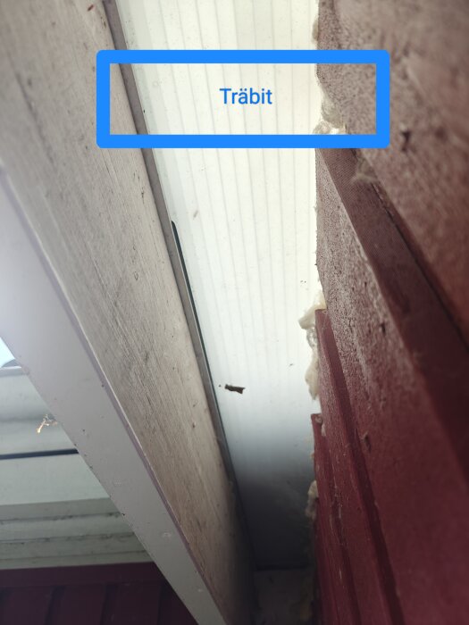 Träbit intill plasttak med synlig lös regel och plastlister på en byggarbetsplats.