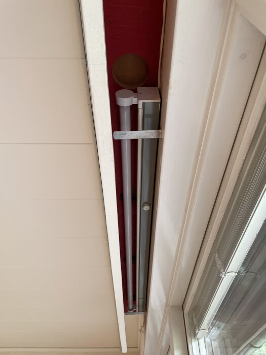 Träpanel med lysrör avinstallerade längs ett fönster i ett hus från 1960-talet.