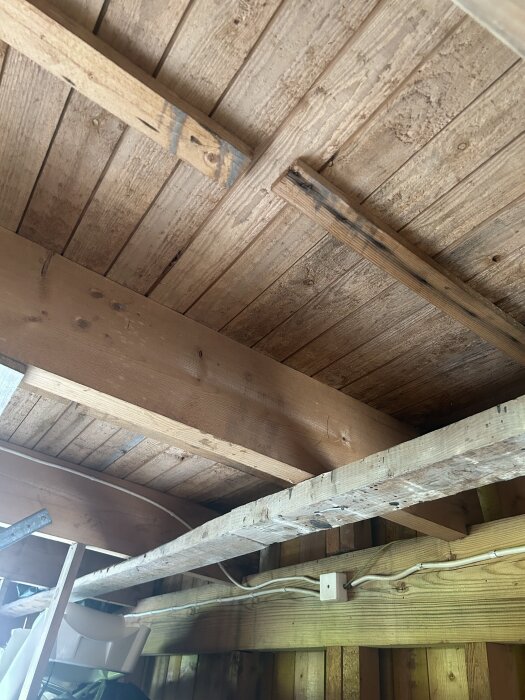Garagetak från 70-talet med synliga brädor och bjälkar, planerat för ombyggnad till förråd med isolering, fokus på rätt steg och undvikande av misstag.
