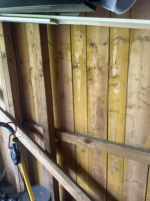 Vägg i garage från 70-talet med synliga träreglar och träpanel, redo för ombyggnad till förråd.