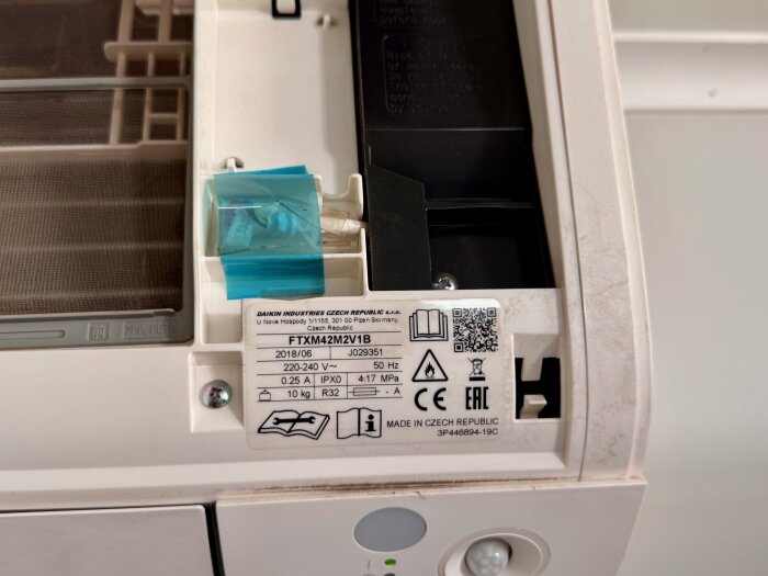 Närbild på en apparat med en etikett som har modellnumret FTXM42M2V1B och annan teknisk information.