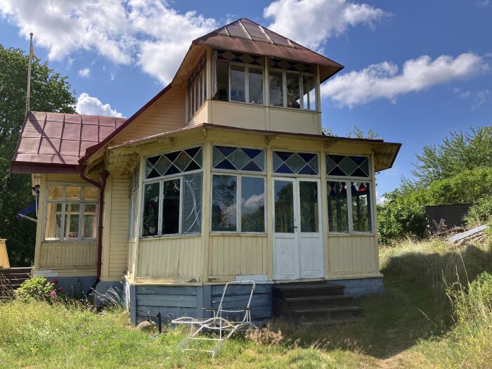 Glasveranda på ett gammalt sommarhus från 1890 på en ö i Mälaren, med skadat trä och behov av renovering.