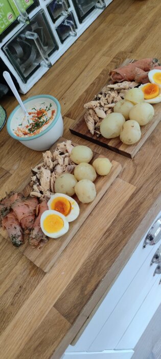 Hemrökt vättersik och köpt gravad lax serverade med potatis, ägg och sås på en träskärbräda.