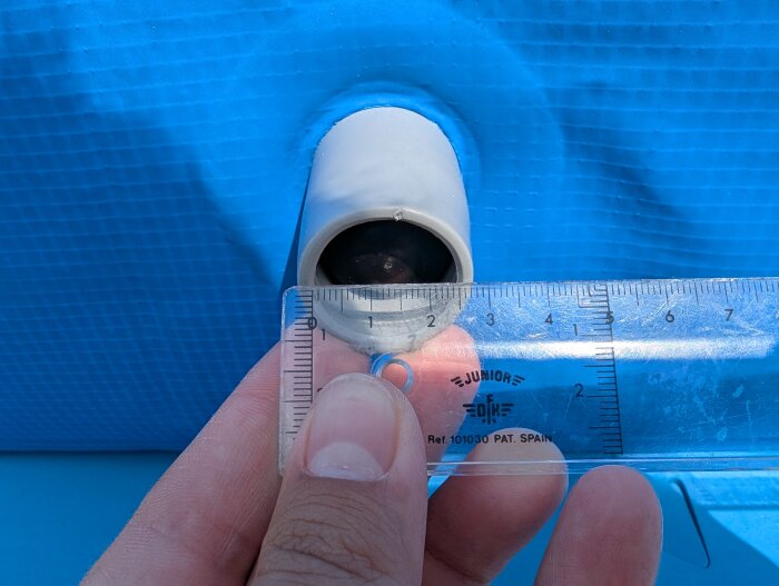 Utloppet på en blå barnpool med en gummianslutning mätt med en linjal som visar ca 25 mm innermått.