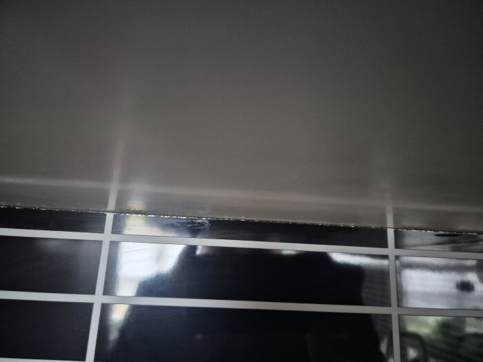 Närbild av köksstänkskydd där kanten har börjat lossna.