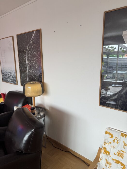 Vardagsrumsvägg med tavlor, lampa och soffhörn; enligt inlägg ska det finnas en igensatt dörr bakom tavlan.