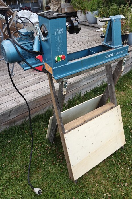 Blå svarv med träbänk på trädäck i trädgård.