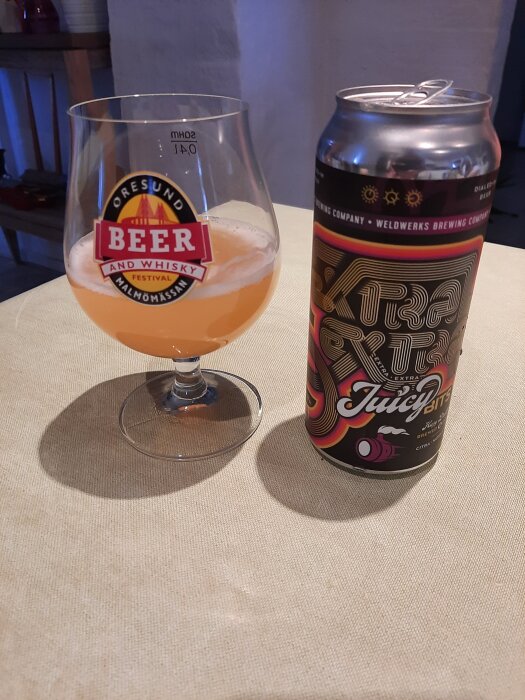 Glas med öl från Öresund Beer and Whisky Festival och en burk WeldWerks Extra Extra Juicy Bits på ett bord.