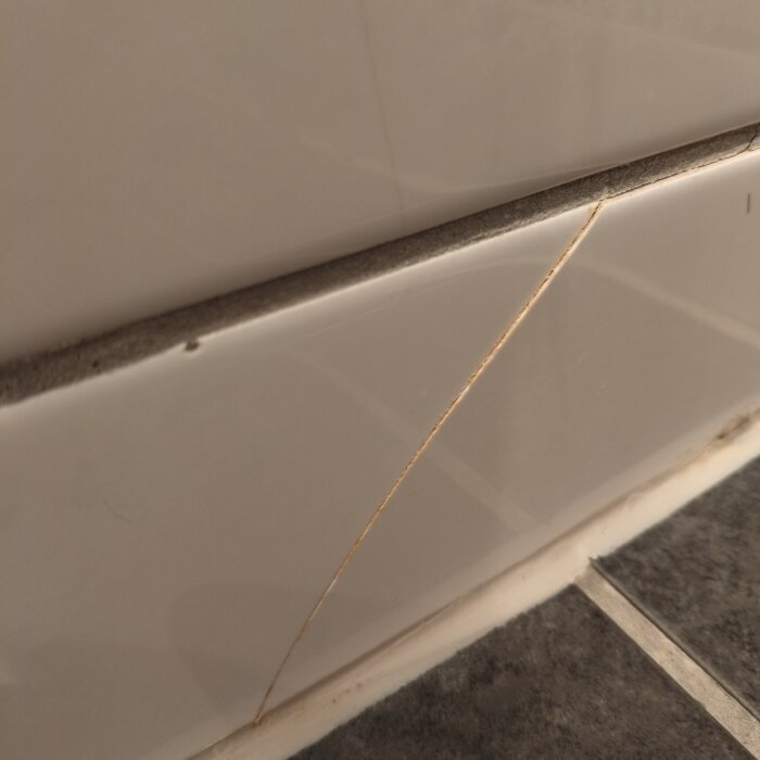 Kakelplatta i badrum med vertikal spricka.