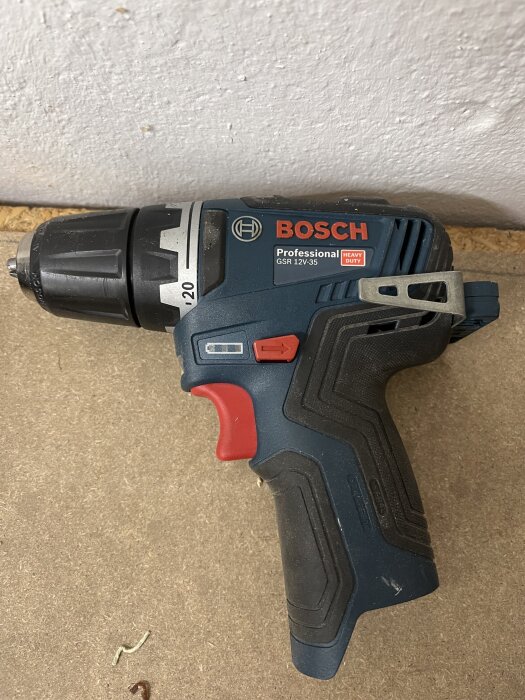 En Bosch Professional 12V skruvdragare ligger på ett trägolv med texten "Heavy Duty".