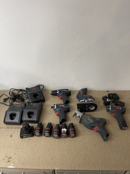 Flera 12V Bosch elverktyg och tillbehör på ett bord, inklusive batterier och laddare, som är till salu.
