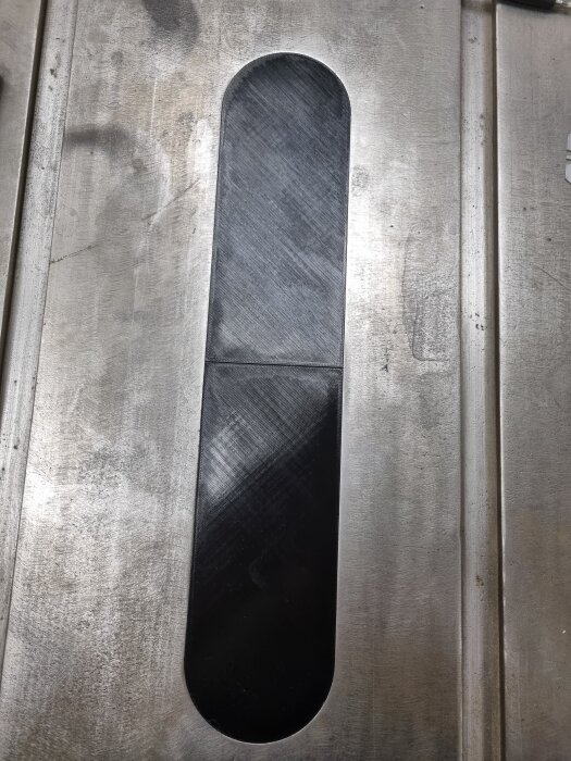 3D-printad fräsmall i en metallinsats på ett arbetsbord, skapad för att passa en klinga med minimalt spel.