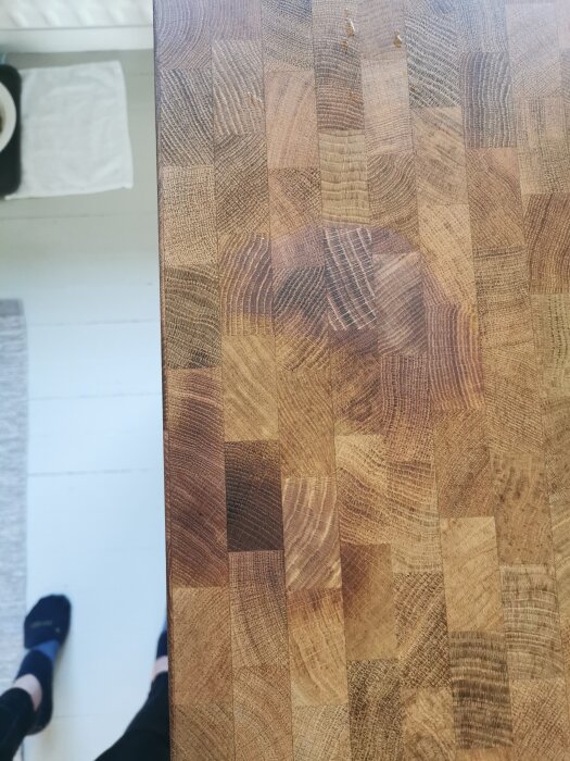 En träfanerad bänkskiva med mörkare och mattare område mitt på, omgiven av ljusare yta.