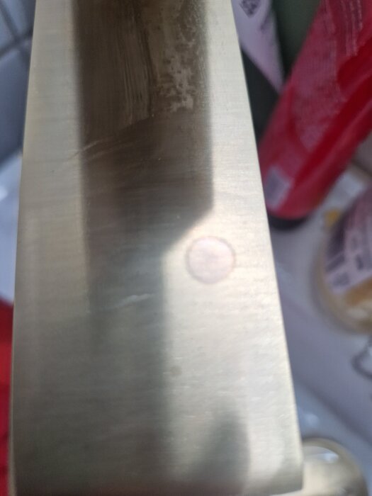 Mässingkran med ljus cirkelfläck på ytan i närbild.