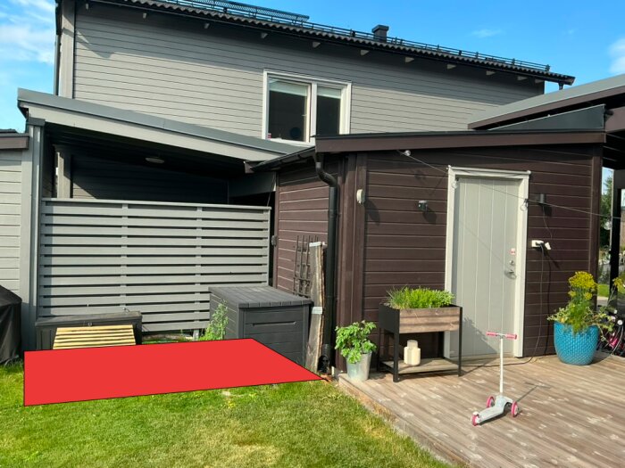 Förslag på bastuplacering markerad med röd yta bredvid ett förråd på en liten tomt.