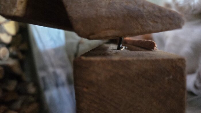 Närbild av trasigt armstöd på kökssoffa med synlig spik, trädetaljer och spricka som diskuteras för reparation.