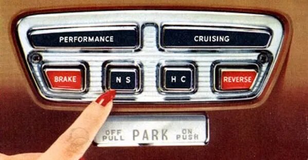 En vintage bilpanel med knappar för prestanda och kryssning, broms och backning, och en fingerpekare som trycker på en knapp.